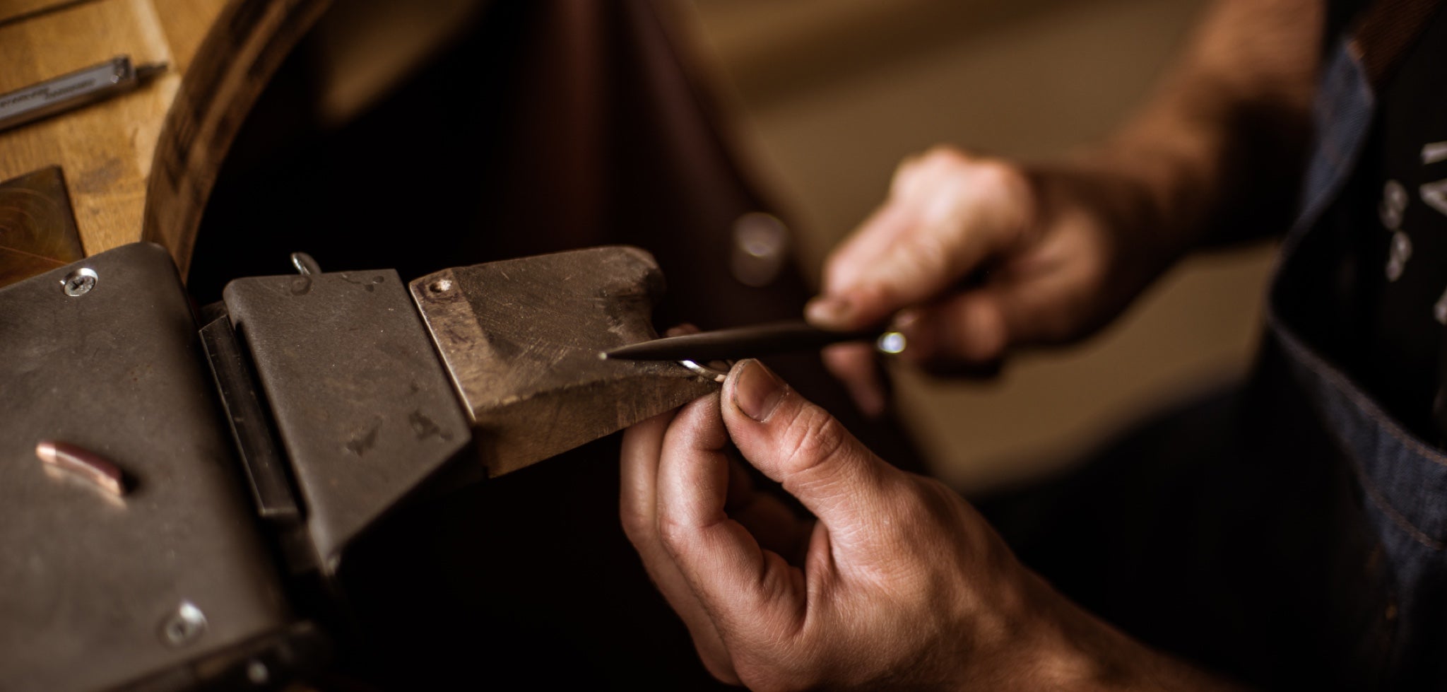 Man crafting a gold wedding ring at a workbench
