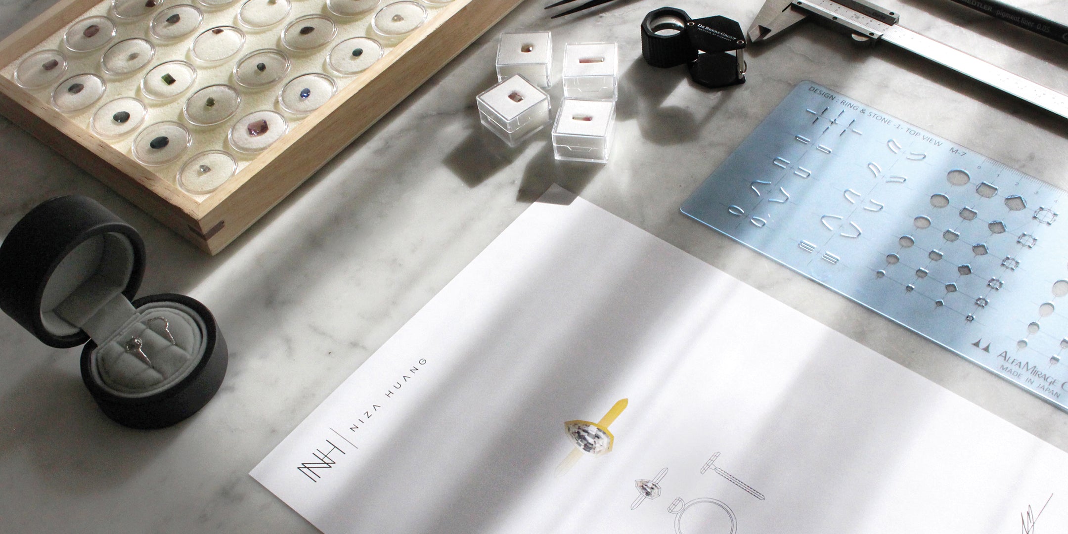 Niza Huang studio shot with bespoke engagement ring designs on a workbench