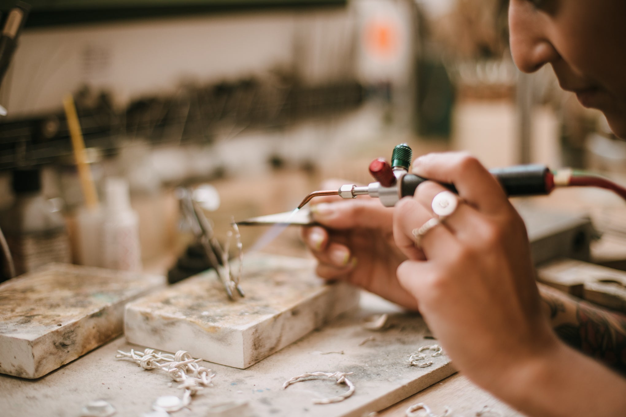 Independent jeweller making a pair of earrings at her workbench