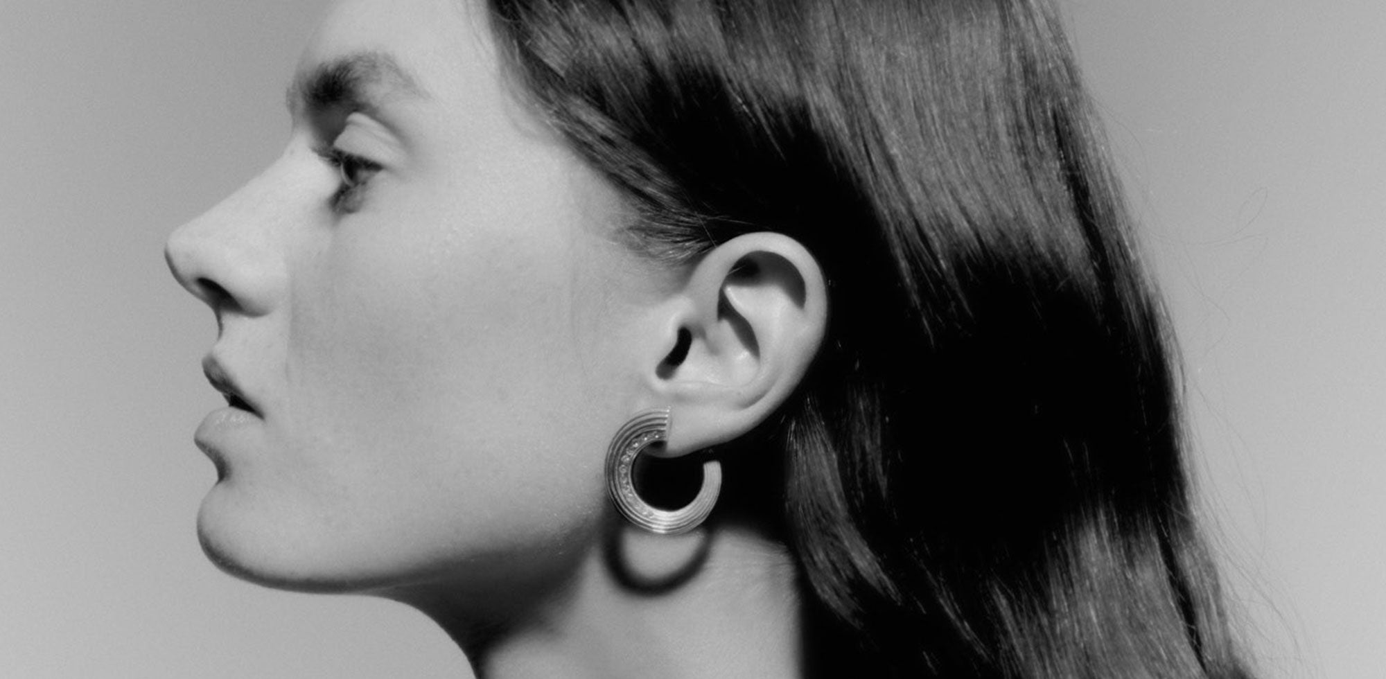 Black and white photo of a model wearing a hoop earring by independent designer Deve