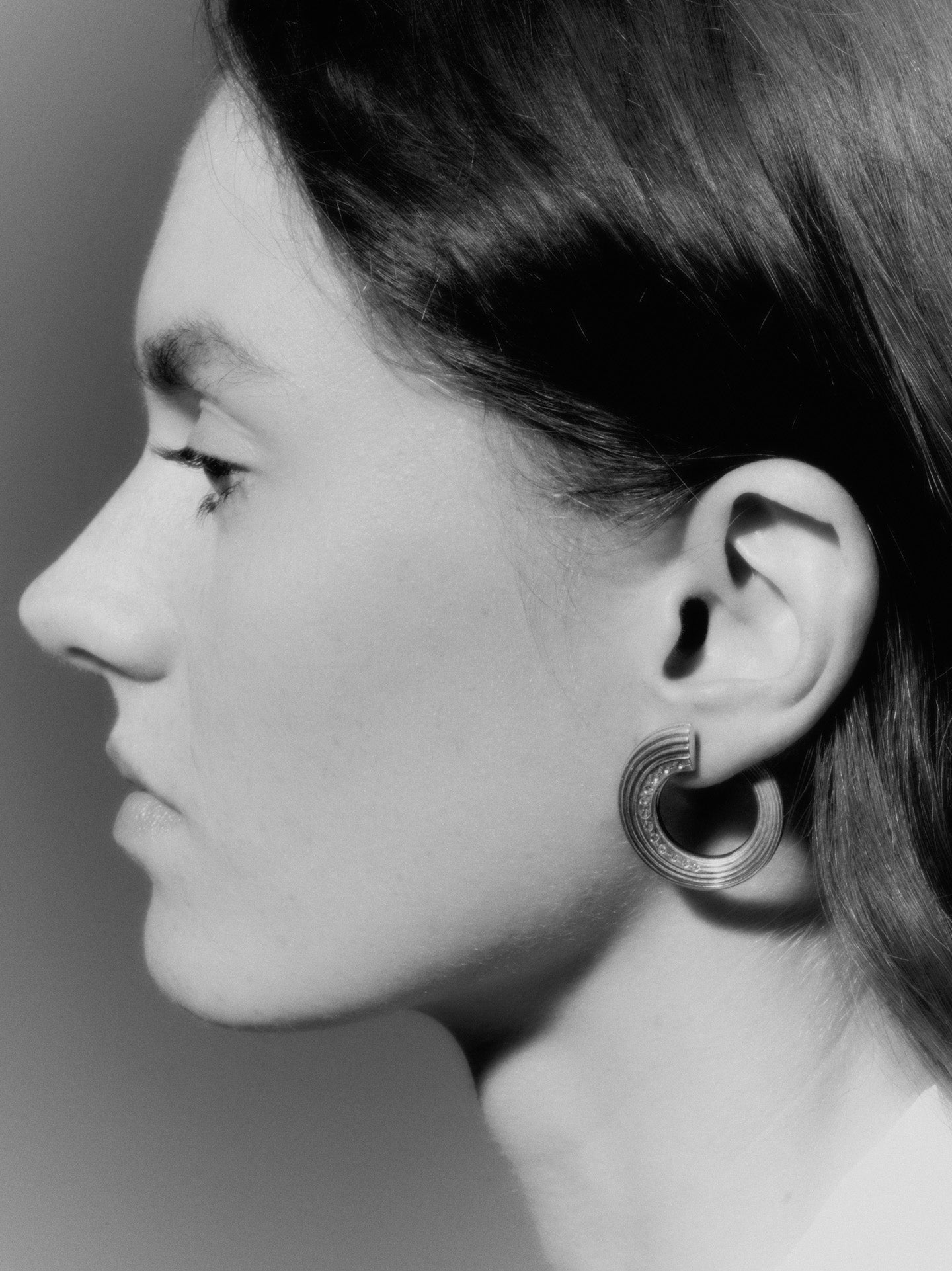 Black and white photo of a model wearing a hoop earring by independent designer Deve