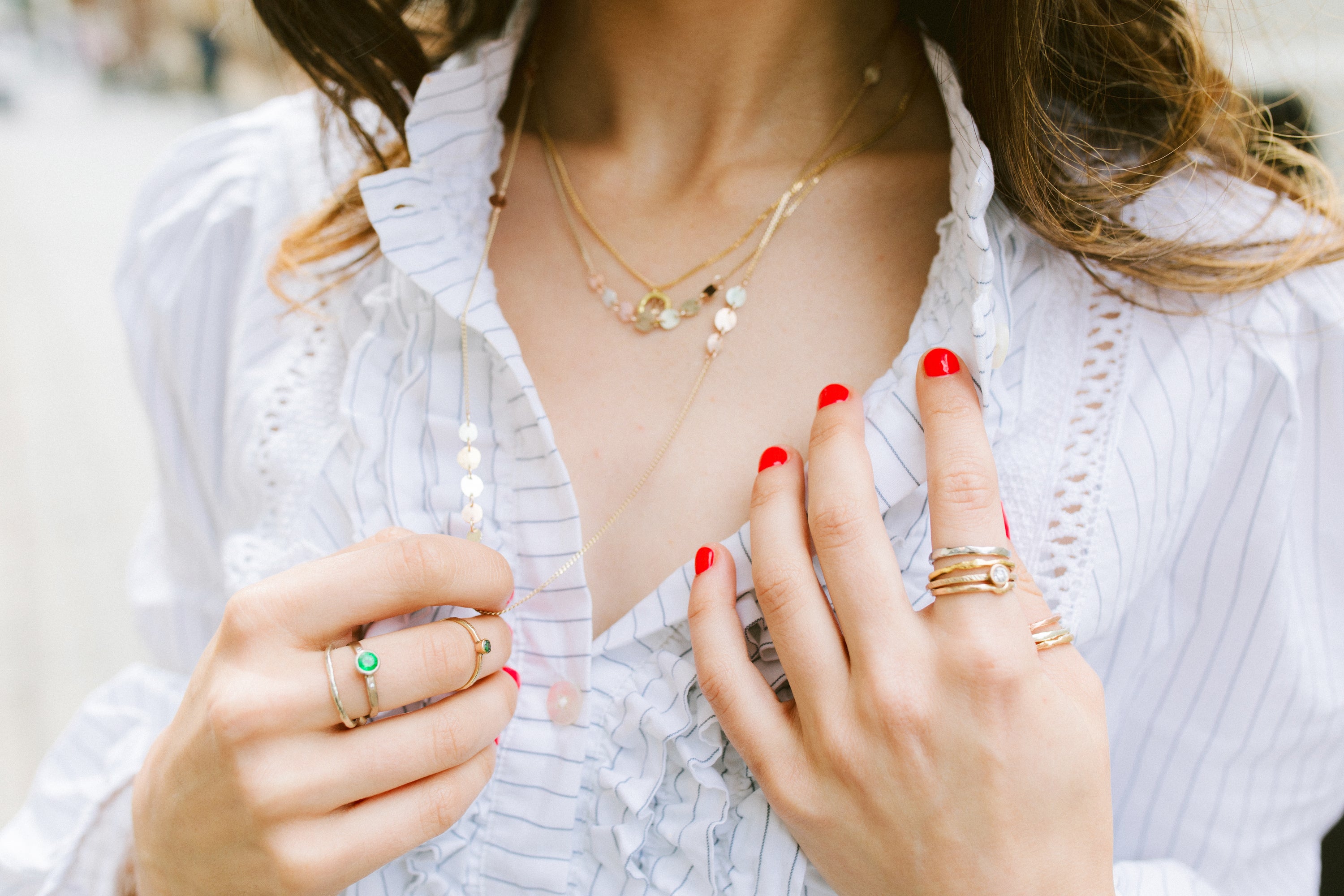 Woman with orange nails wearing loose blouse and jewellery handmade by Erin Cox in Devon