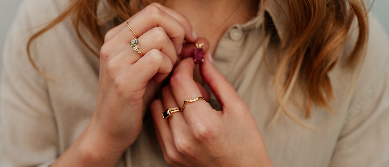 White female wearing handmade bespoke rings and a handmade bespoke gold necklace