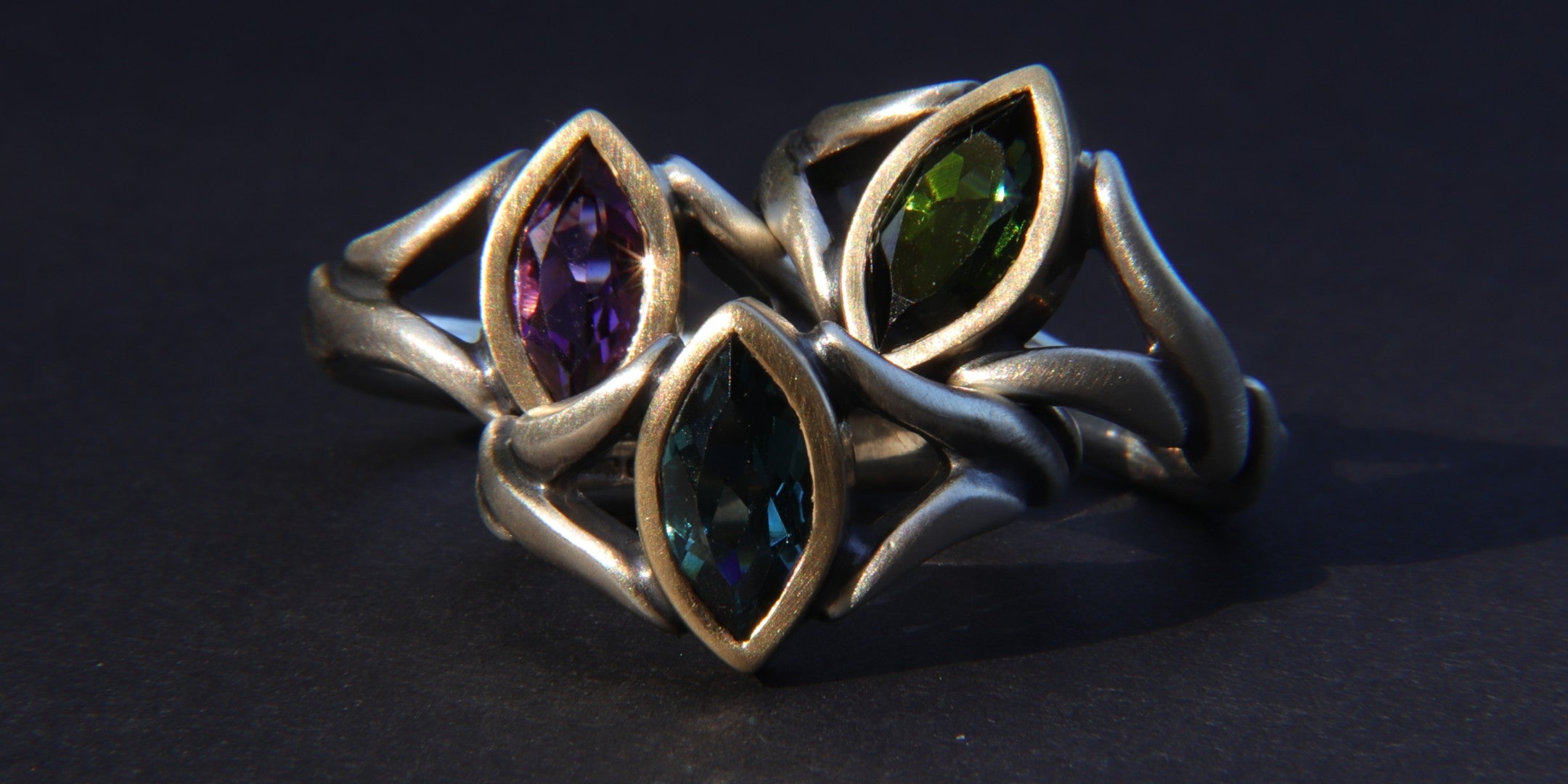 Three solitaire engagement rings stacked against a dark background