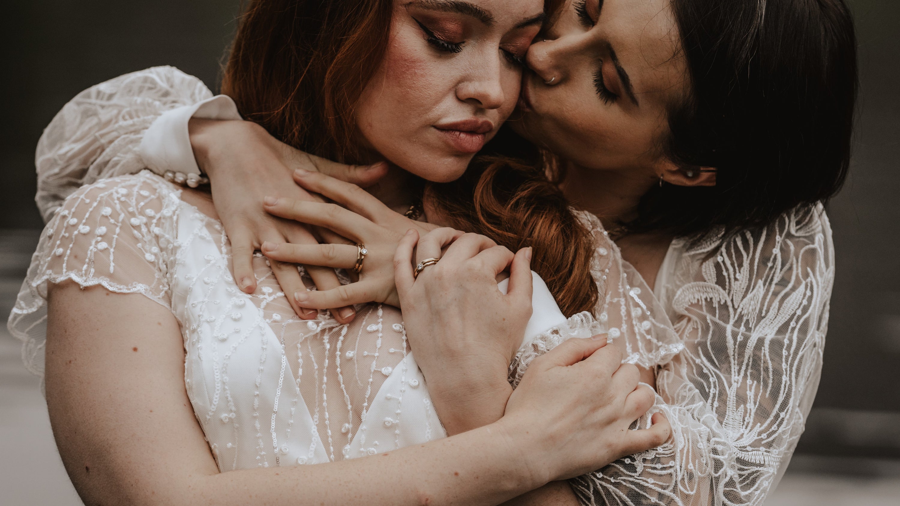 two brides embrace, wearing bespoke handmade wedding jewellery