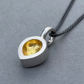 sterling silver chunky teardrop pendant with 24k gold keum boo on oxidised chain on grey background