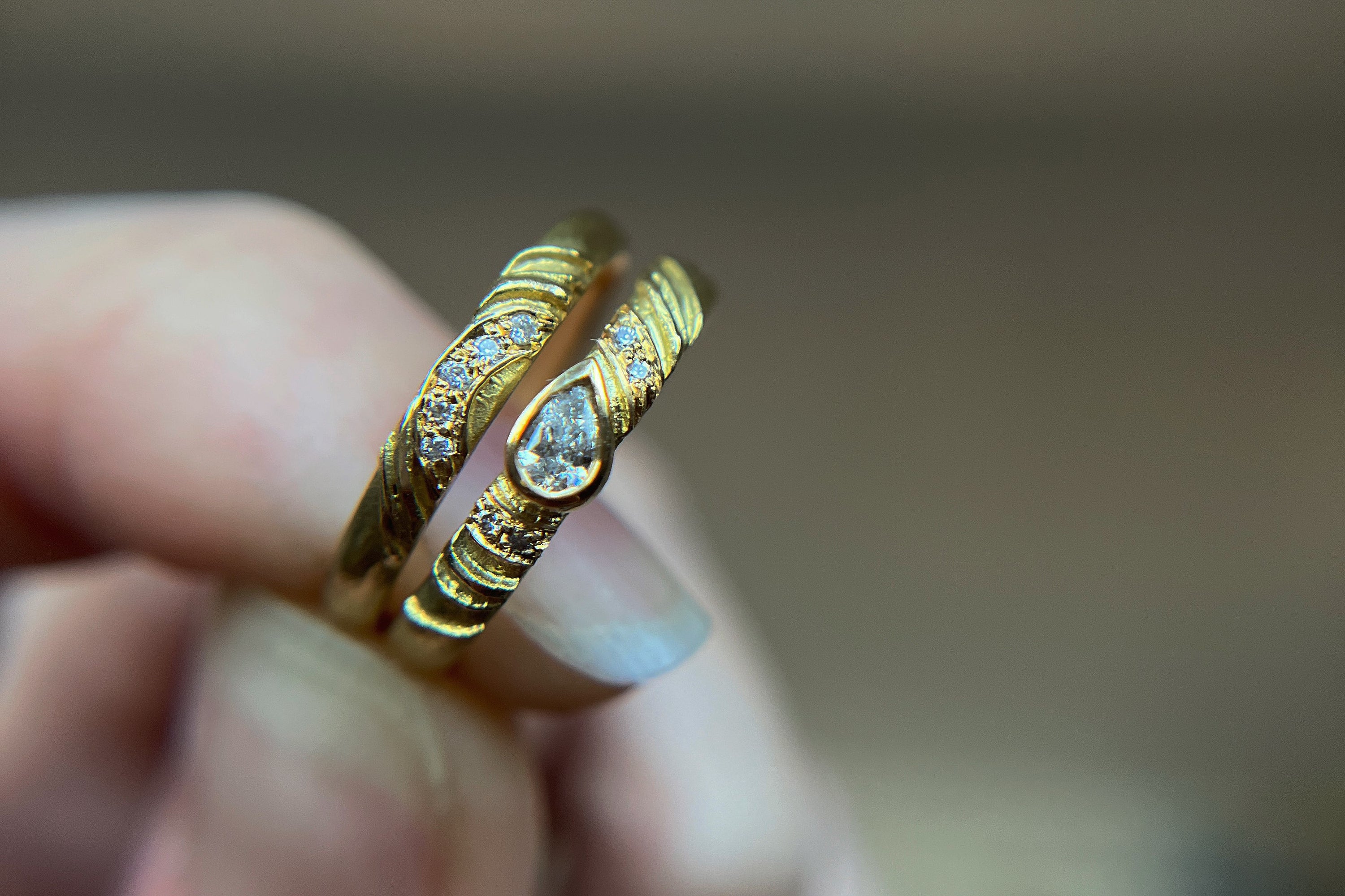Two handmade bespoke gold wedding rings being held by independent jeweller Claire Macfarlane