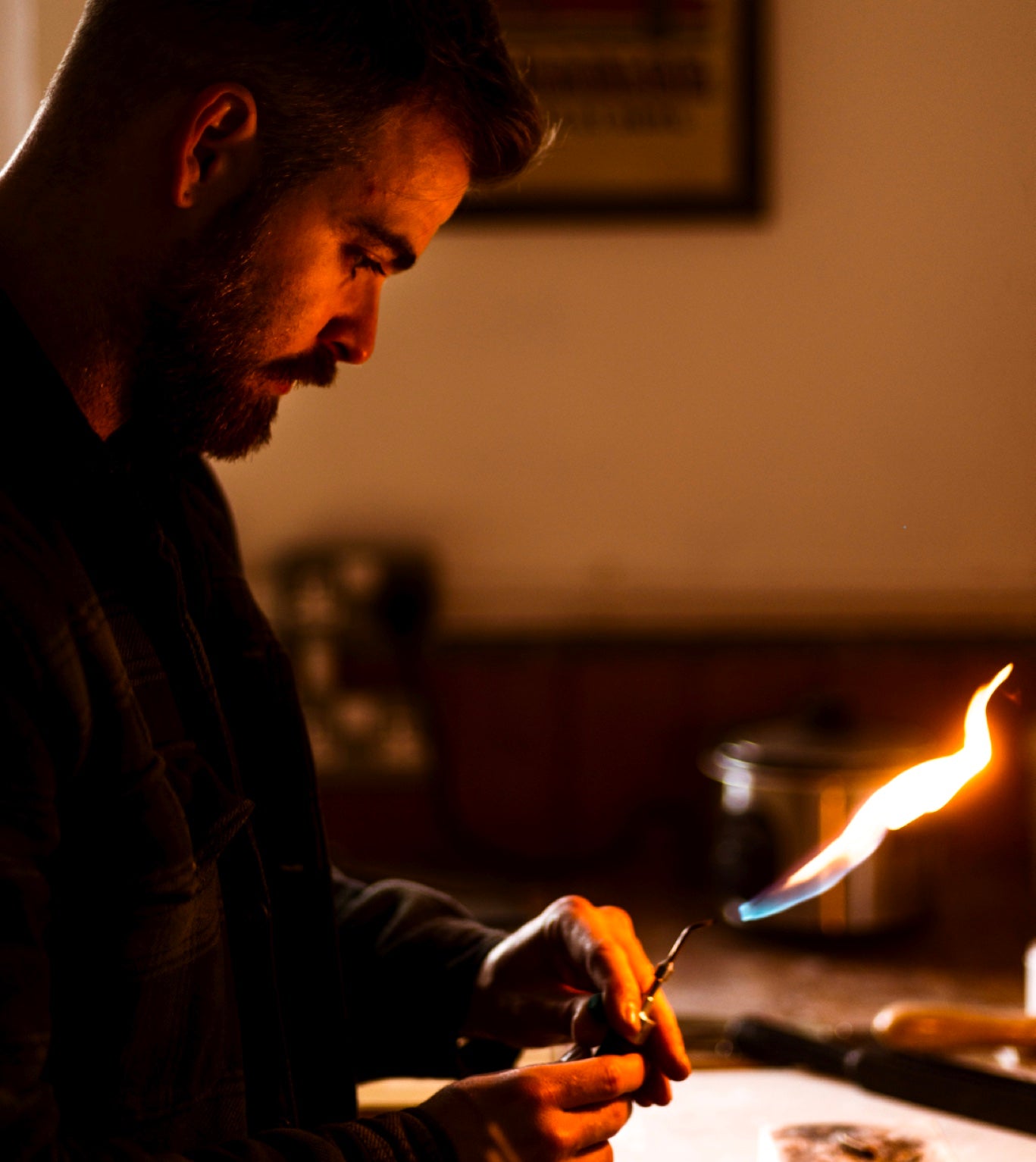 Jeweller looking at a flame inside his workshop