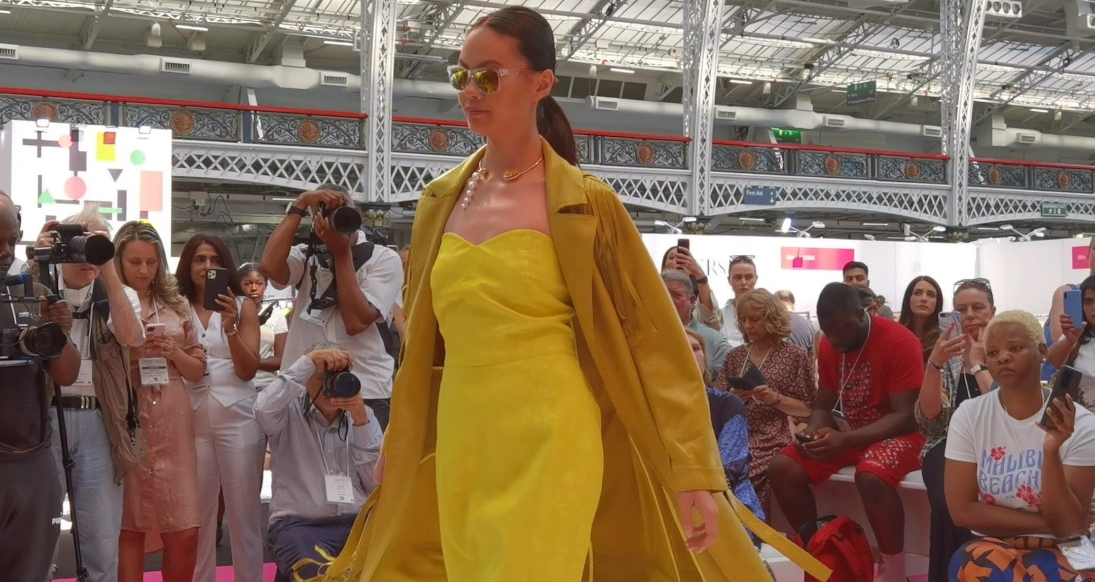 Female model on a catwalk, wearing a yellow dress and bespoke jewellery by Georgia Wang