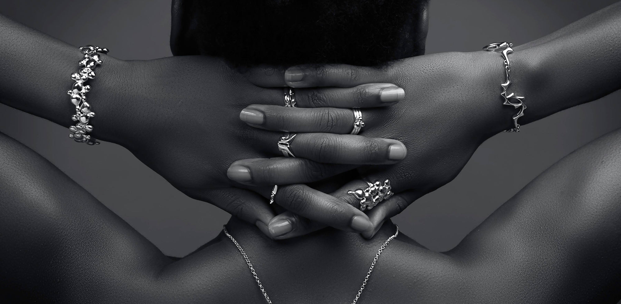 Model facing away from the camera with her hands behind her head, wearing handmade silver jewellery