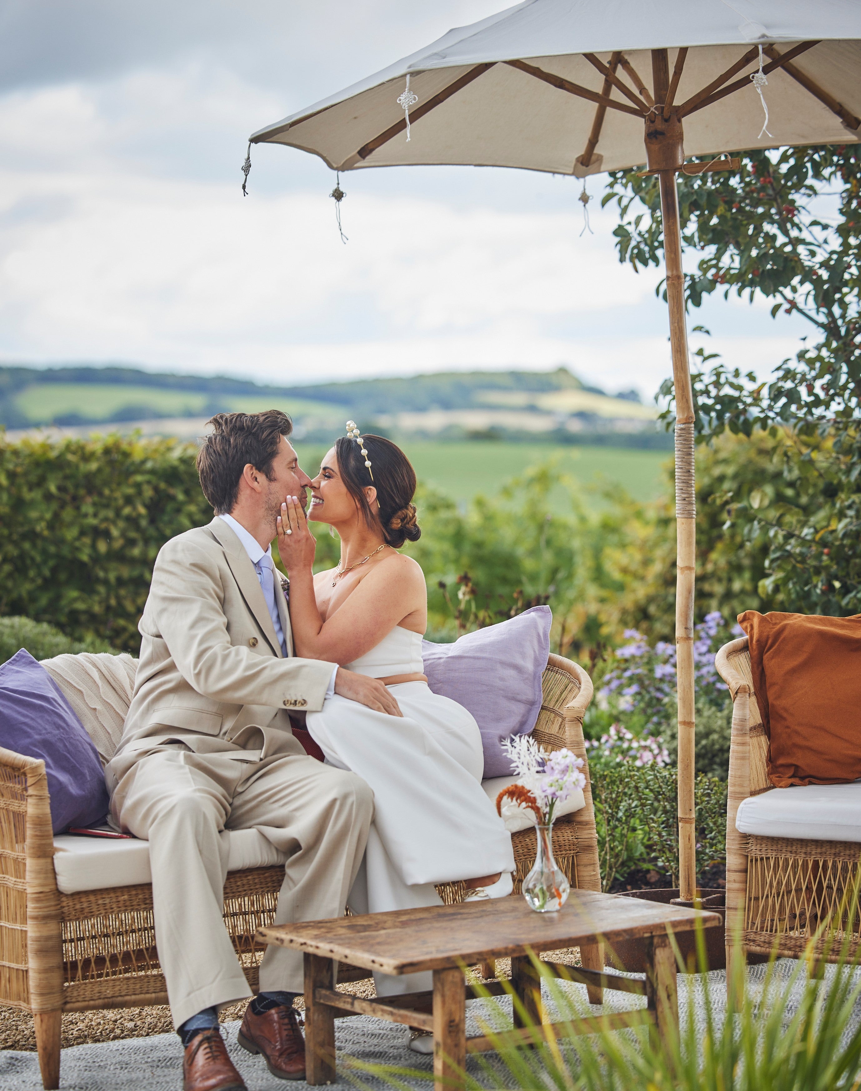 Bride and Groom seated outside under an umbrella