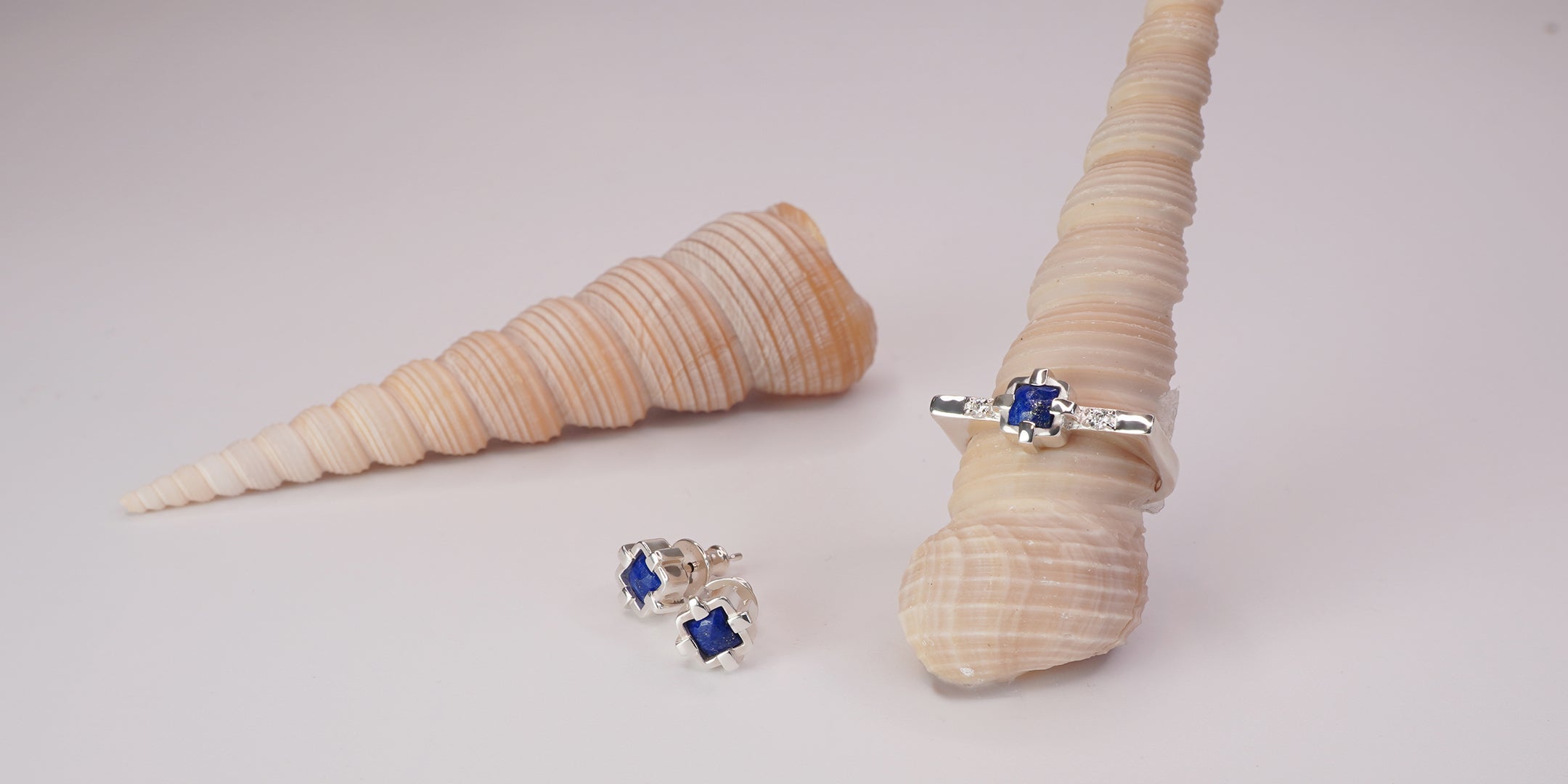 Silver and sapphire ring next to two silver sapphire earrings