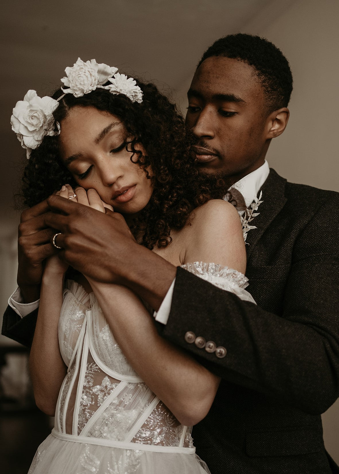 Black bride and groom embracing, both wearing bespoke handmade jewellery
