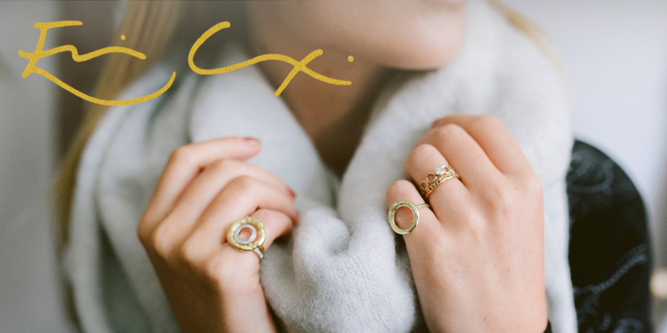 Woman wearing bespoke rings made by Erin Cox, holding a grey scarf