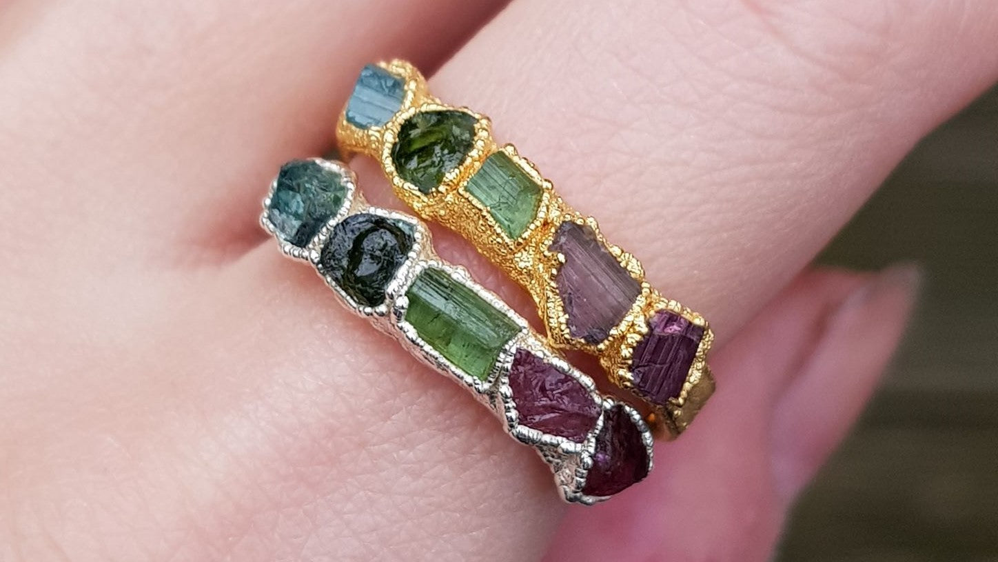close up of two rings each set with 5 rough gemstones