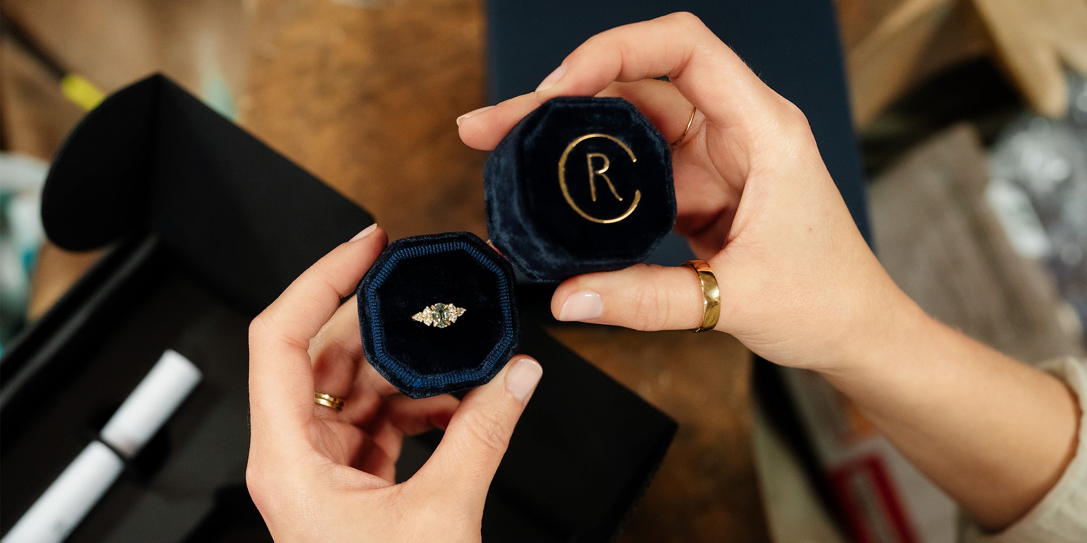 Woman's hands holding a handmade bespoke engagement ring in a ring box