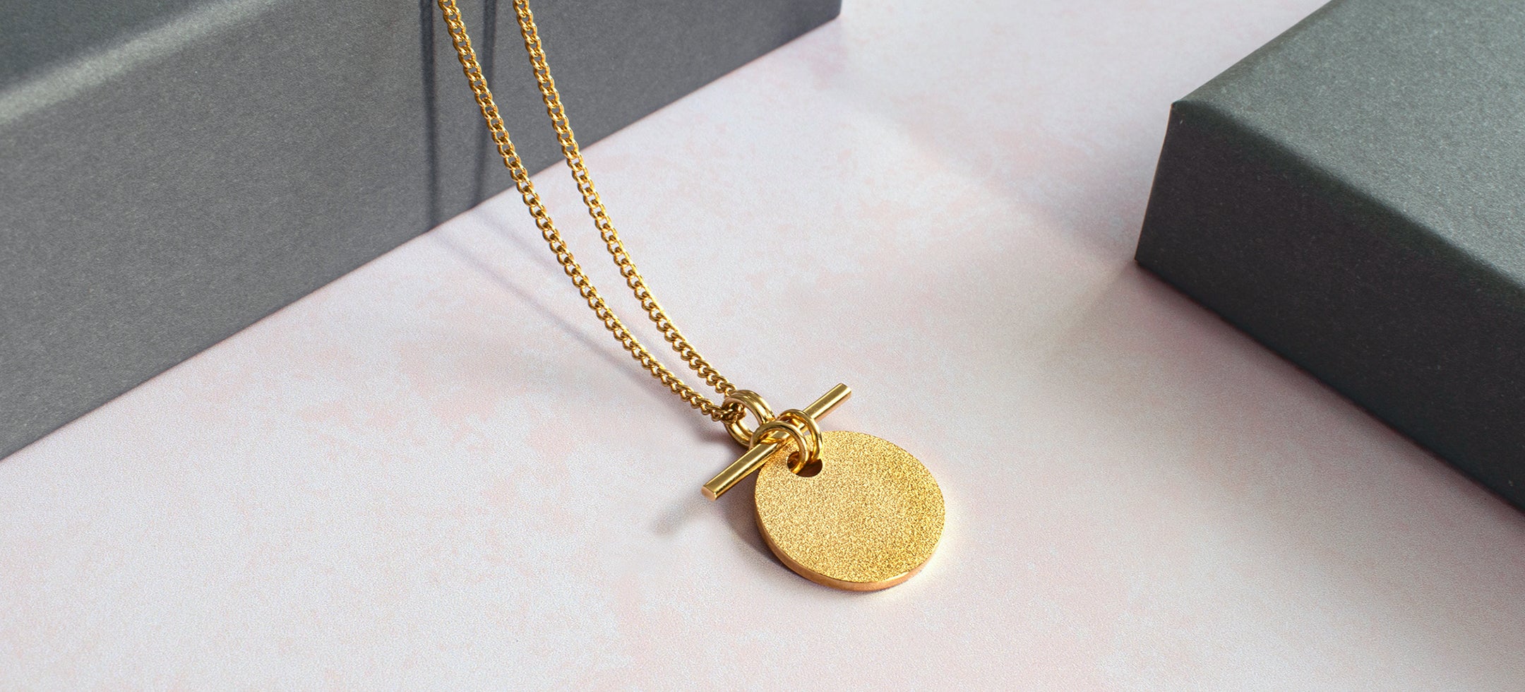 A handmade gold necklace against a grey backdrop
